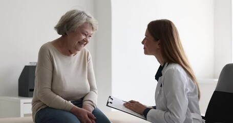 Female doctor in white coat listen to older woman tell about chronic disease, health complaints, affliction symptoms, therapist take notes, fill history form during patient visit. Nursing, elder care - Powered by Adobe