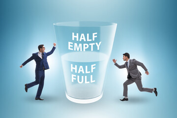 Businessman in half empty half full glass concept