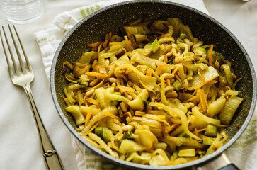 Skillet with sautéed fennel with orange. Traditional French dish. Fennel, pine nuts and orange
