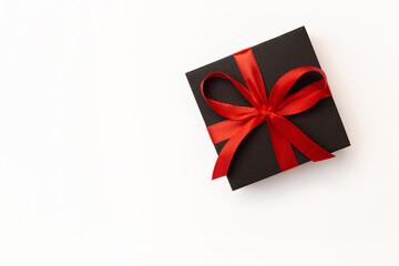 Flat lay of black present box with red ribbon on the white background