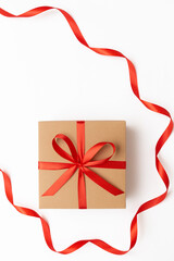 Flat lay of craft present box with red bow and ribbon on the white background