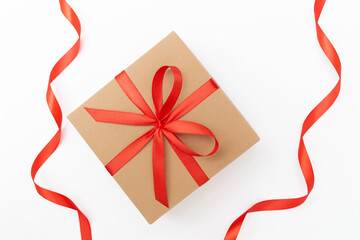Flat lay of craft present box with red bow and ribbons on the white background