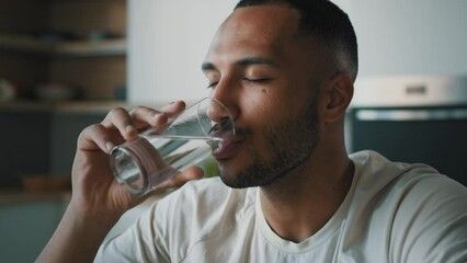 African American healthy sportsman ethnic male guy man athlete sporty trainer indoors drink still cold water with glass drinking refreshment fresh nutrition aqua balance body health care weight loss