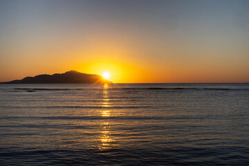 sunset in the sea, the sun rises after the mountain to the sea.