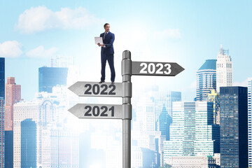 Fototapeta na wymiar Businessman on signpost from 2022 to 2023