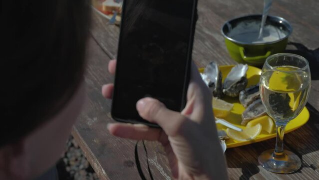 A Girl Takes Pictures Of Oysters On The Smartphone In An Street Restaurant