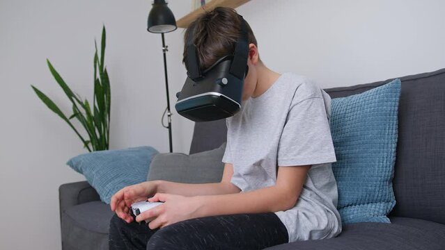 Caucasian boy enjoying at home, gaming using VR box, virtual reality goggles, and simulator, moving and physically interacting with a virtual world, handheld shot.