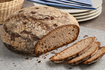 Fresh traditional German whole Bauernkloben brot and slices, mixed rye loaf of bread, close up on a cutting board 