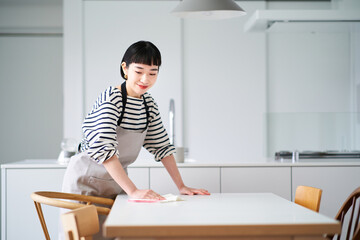 ダイニングテーブルを拭く若い女性