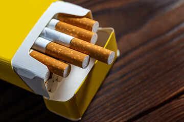 Cigarettes in a pack. Yellow filter. Harm to health. Bad habit. A pack of cigarettes on the table.