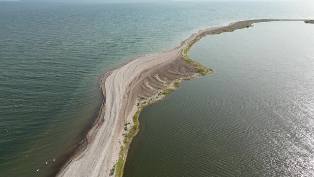 Shooting from a drone flying over a long sandy spit. Sand spit and turquoise water. Baltic sea. Aerial sunset view of sandy beach, Beautiful aerial drone wide view of Curonian spit.