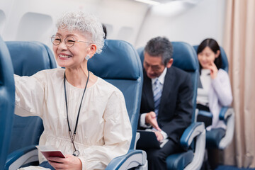 機内エンターテイメントを楽しむ高齢の女性