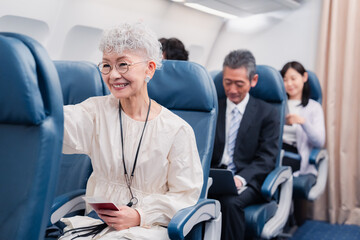 機内エンターテイメントを楽しむ高齢の女性