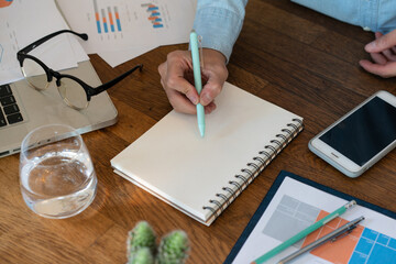 Non people imagery of desk set-up , work environments . work at a desk in a home office. .Writing on a notepad while working from home.