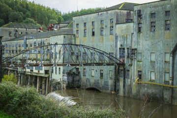 Old abandoned Matrena factory in the river margins with a little waterfall. Old factory in the margins of the Nabao river in the city of Tomar - Portugal