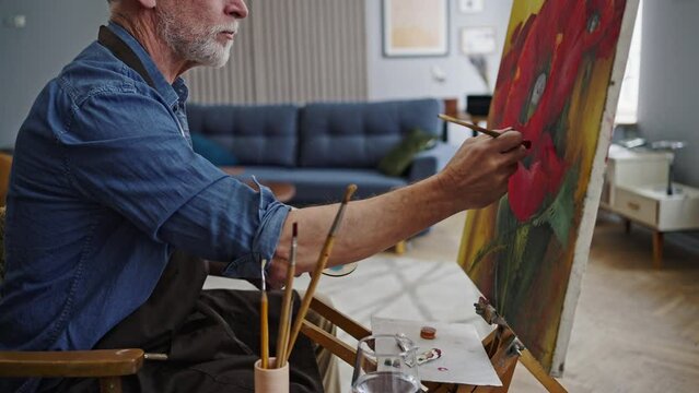 Mature bearded Caucasian man, artist painter, taking his free time to do art, painting on canvas
