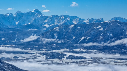 Fototapeta na wymiar Panoramic view of snowcapped mountain summit Mangart and Jalovec in Julian Alps seen from Kobesnock near Bad Bleiberg, Carinthia (Kaernten), Austria, Europe. Snow covered winter wonderland foreground