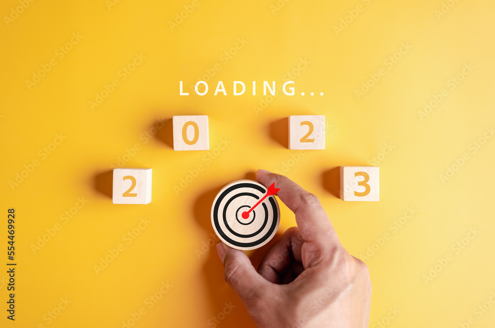Poster Target plan next year 2023 concept, Hand putting wooden cube block for loading progress from 2023 to countdown merry christmas and happy new year..