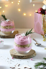 Strawberry - banana dessert with cookies in a glass stands on a wooden stand on a white Christmas background with bokeh 
