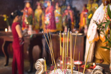 Burning incense sticks and blurred woman praying at Ha Chuong Hoi Quan Pagoda in Cho Lon District, Saigon, Vietnam　ホーチミン・チョロンの寺院　線香と祈る女性　霞彰會館（媽祖天后廟）