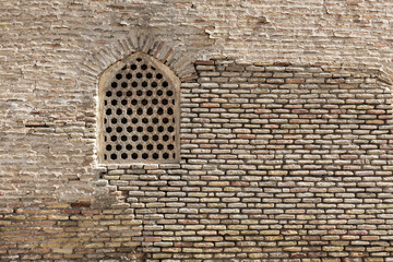 Ancient partially rebuilt brick made wall with window behind stone lattice Bukhara Uzbekistan