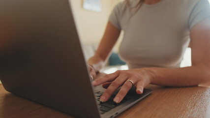 Close-up of young woman's hands typing on laptop while sitting at home