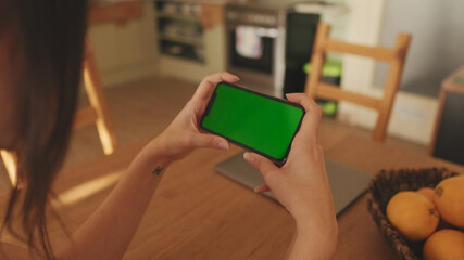 Close-up of young woman's hands using mobile phone green screen chroma key at home