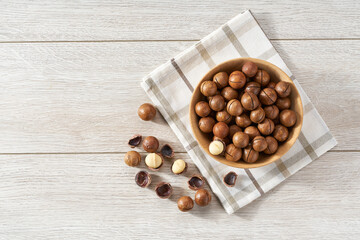 Macadamia  in wooden bowl on white table with copy space. Top view
