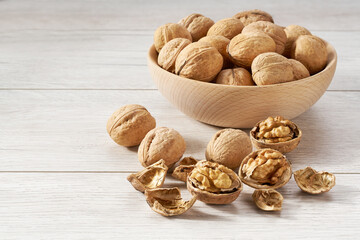 walnuts in wooden bowl on white table.