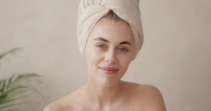 Body treatment. Beautiful woman wrapped in towel looking camera