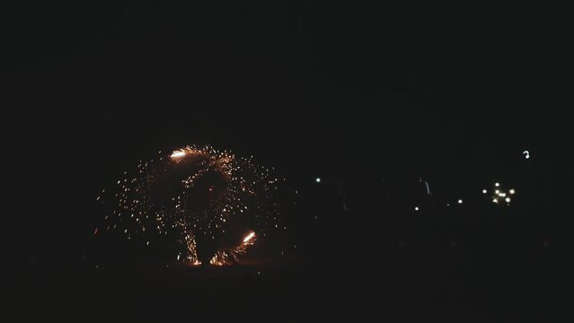 Fire show. Unrecognizable artist performing fire show outdoors at evening time. Woman is turning around with fire sticks.