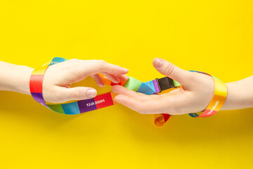 LGBT symbol - wo women's hands wrapped in rainbow ribbon stretch one to one, the concept of the difficulty of same-sex love and separation - 554476506