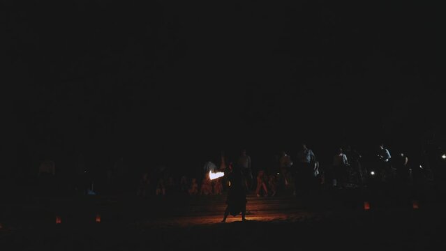 Fire show. Unrecognizable artist performing fire show outdoors at evening time. Woman is turning around with fire sticks.