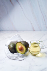 Jar with oil and ripe fresh avocado on table