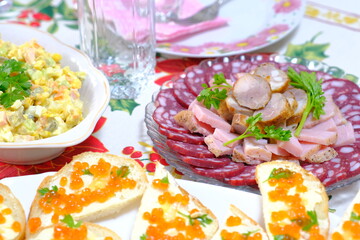 Ukrainian Easter festive dishes. Festive table setting. Bright colored eggs, cake Paska, traditional salad olivier, fried fish, sandwiches with red caviar, vegetables, green, homemade sausage, herring