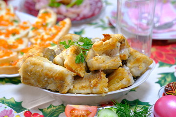 Ukrainian Easter festive dishes. Festive table setting. Bright colored eggs, cake Paska, traditional salad olivier, fried fish, sandwiches with red caviar, vegetables, green, homemade sausage, herring
