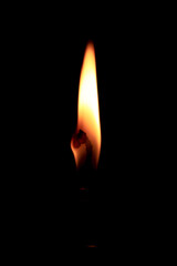 The flame of a burning candle in absolute darkness. Burning candle on a black background