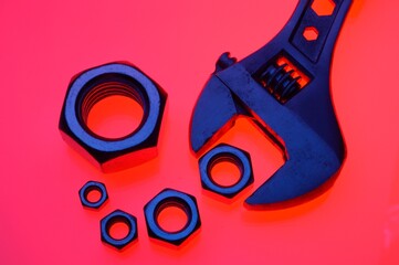 adjustable wrench and nuts of different sizes on a red background.Close-up