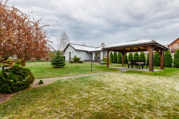 Guest house with green lawn and plants, with a small amount of snow falling