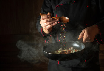 Cooking fresh vegetables. The cook adds pepper to a steaming hot pan. The idea of European cuisine...