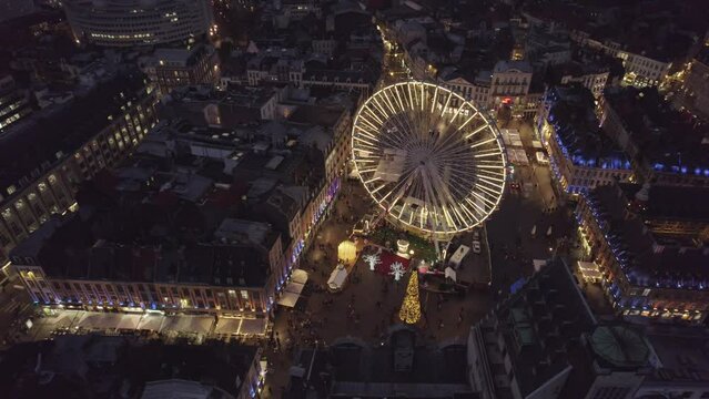 Aerial drone view of Lille, France, at Christmas by night. Amazing 4K video of wheel, Grand Place and beffroi