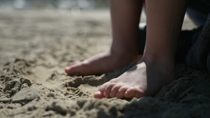 Fototapeta na wymiar Child feet standing up at beach feeling the sand barefoot. Kid foot walking outside at ocean shore