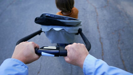 Mother POV pushing stroller outside at park. Hands closeup point of view carrying child strolling...