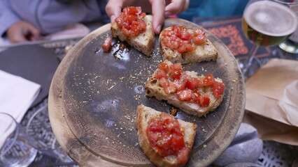 Italian Appetizer Bruschetta on Wooden Plate at restaurant. Bread and tomatoes