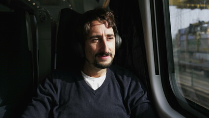 One passenger putting headphone commuting to work or study inside high speed train. Man listening to music podcast or audiobook seated by window