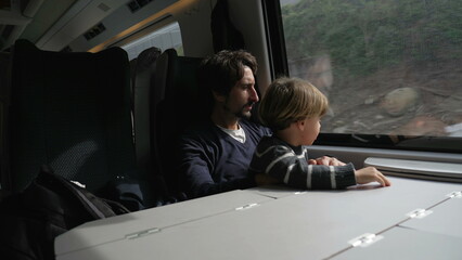 Father and son traveling by train together. Passengers seated by high speed window