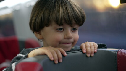 Child standing on train seat traveling inside high speed train. closeup face of one boy travels on vacation