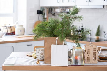 Paper packages mock up are on kitchen served table decorated for Christmas. Shopping and gifts, present and ready meals are delivered and prepared for the new year