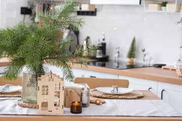 Festive Christmas decor in white kitchen, festive breakfast, white scandi interior. The figure of a cozy house ion the set table. New Year, mood, cozy home. Copy space