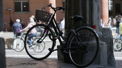 Fototapeta na wymiar Bicycle leaning on old European column. Bike parked outside. Urban alternative transportation